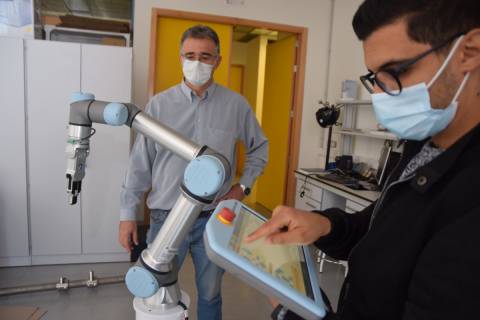 Marouane Salhaoui, en primer término, junto a uno de los directores de la tesis, Antonio Guerrero, programando un robot colaborativo.